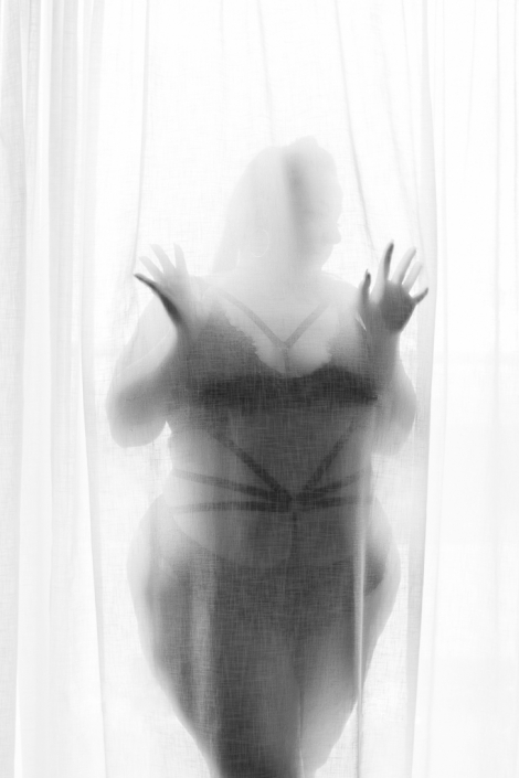 Curvy Göttin steht hinter einem transparenten Vorhang
