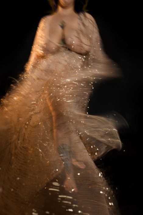 Bewegungsunschärfe, tanzende Frau in goldenem, transparentem Kleid